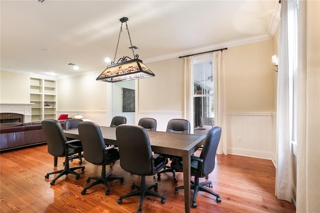 dining room featuring built in features, light hardwood / wood-style flooring, and crown molding