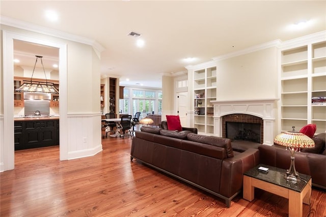 living room with light hardwood / wood-style floors, sink, and ornamental molding