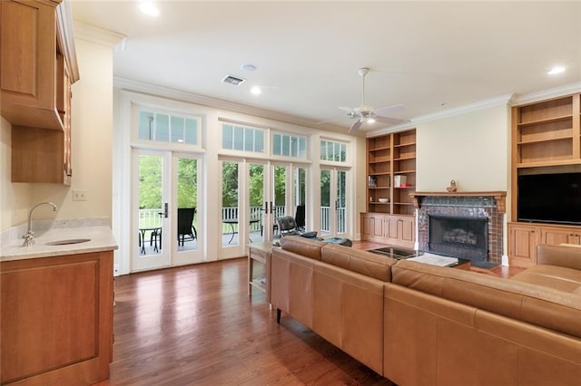 living room with sink, a fireplace, dark hardwood / wood-style floors, ceiling fan, and ornamental molding