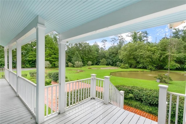 wooden terrace featuring a water view and a lawn