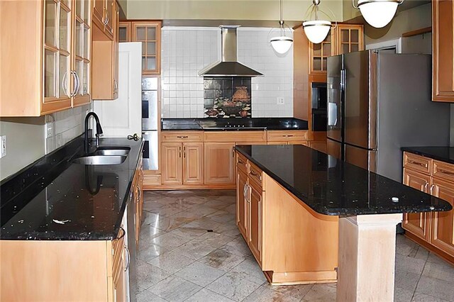 kitchen with tasteful backsplash, wall chimney range hood, a center island, hanging light fixtures, and sink