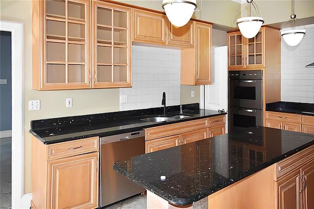 kitchen featuring multiple ovens, sink, dark stone counters, a center island, and stainless steel dishwasher