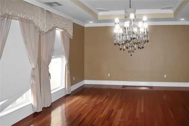 unfurnished dining area featuring an inviting chandelier, a tray ceiling, dark wood-type flooring, and ornamental molding