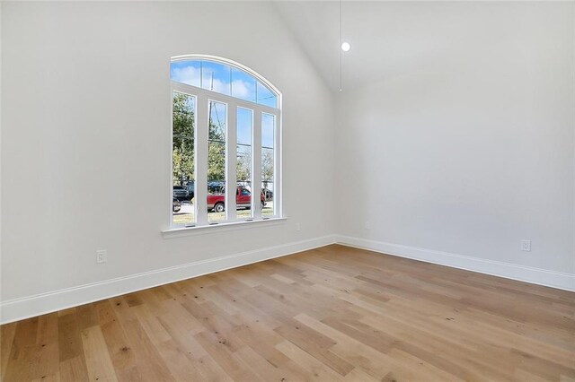 empty room with high vaulted ceiling and light hardwood / wood-style floors