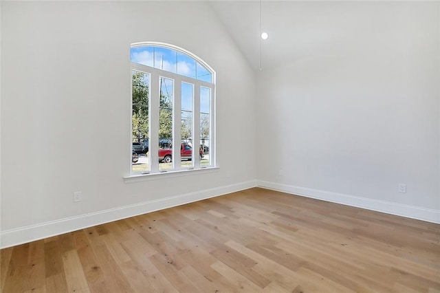 spare room featuring high vaulted ceiling and light hardwood / wood-style flooring