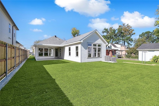 rear view of house with a yard and central AC