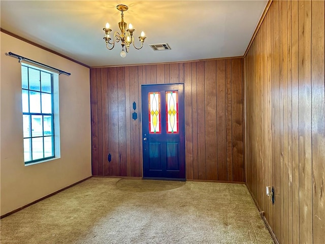 interior space featuring ornamental molding, an inviting chandelier, a healthy amount of sunlight, and wood walls