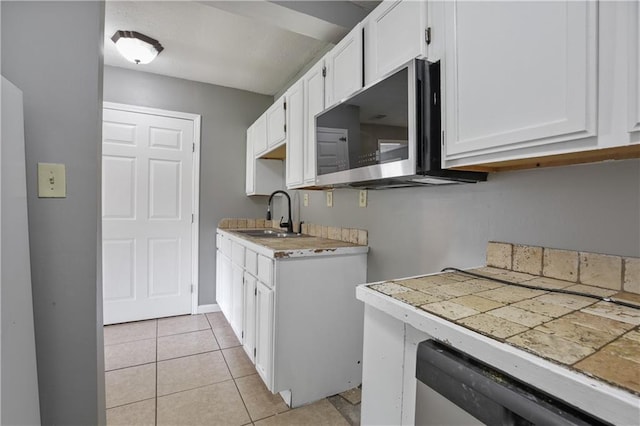 kitchen featuring sink, white cabinetry, light tile patterned floors, and stainless steel appliances