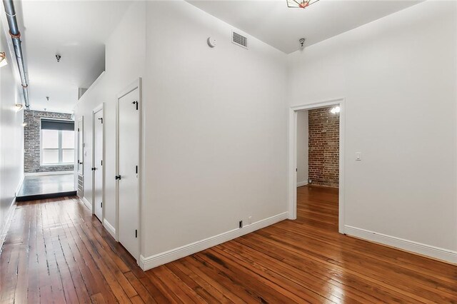 528 Baronne St Unit 503, New Orleans, LA 70113 - hallway featuring hardwood / wood-style floors, brick wall, baseboards, and visible vents