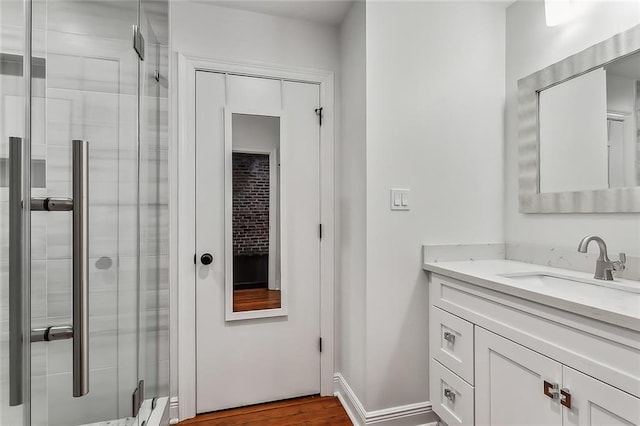 bathroom with hardwood / wood-style flooring, a shower with shower door, and vanity