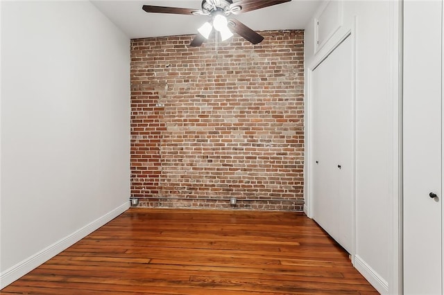 unfurnished bedroom with brick wall, ceiling fan, and hardwood / wood-style floors