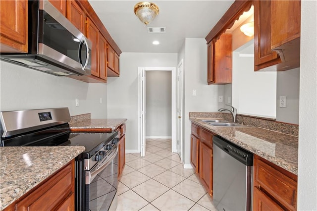 kitchen with stone counters, sink, light tile patterned floors, and stainless steel appliances