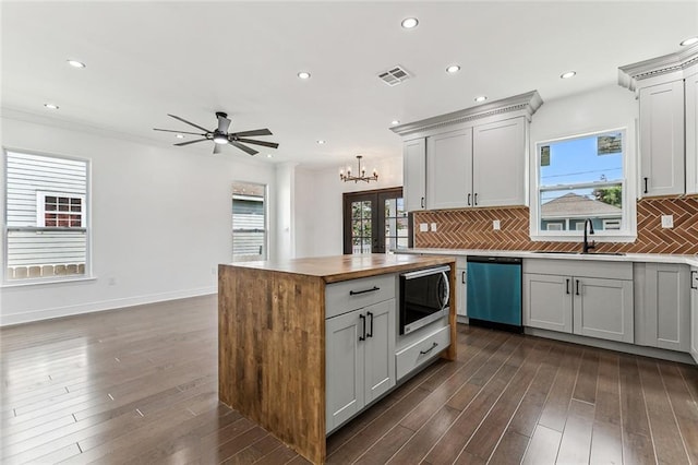 kitchen with tasteful backsplash, stainless steel appliances, sink, ceiling fan with notable chandelier, and dark hardwood / wood-style flooring