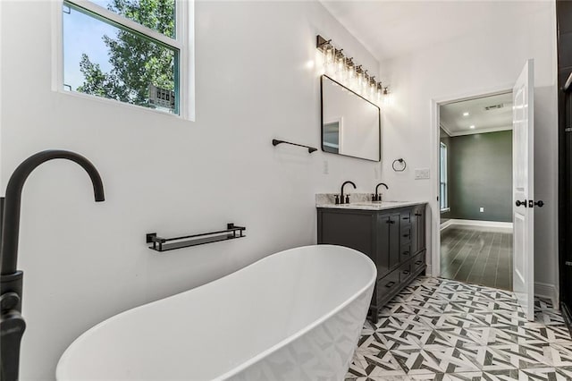 bathroom with tile patterned flooring, a bathtub, vanity, and ornamental molding