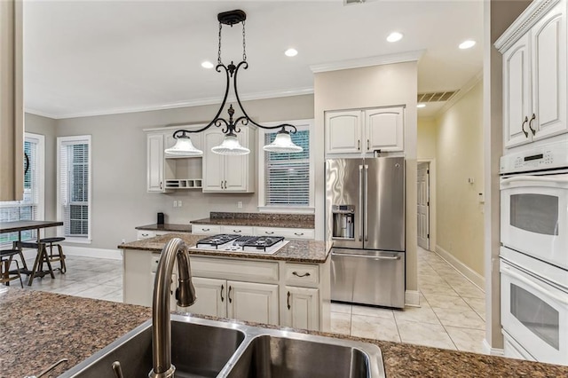 kitchen with appliances with stainless steel finishes, decorative light fixtures, and white cabinets