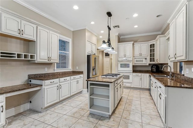 kitchen featuring appliances with stainless steel finishes, dark stone counters, sink, a kitchen island, and white cabinetry