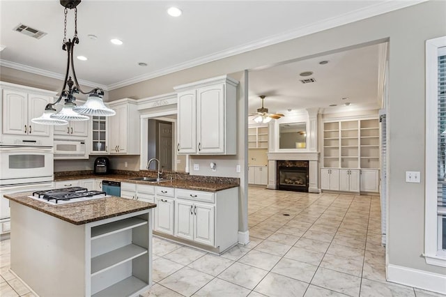 kitchen with ceiling fan, white cabinets, a kitchen island, appliances with stainless steel finishes, and a premium fireplace