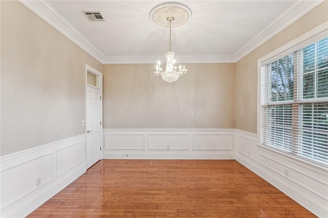 unfurnished dining area featuring hardwood / wood-style flooring, a notable chandelier, and crown molding