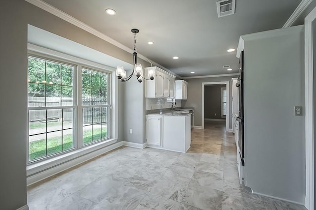 kitchen with white cabinets, a wealth of natural light, ornamental molding, and sink