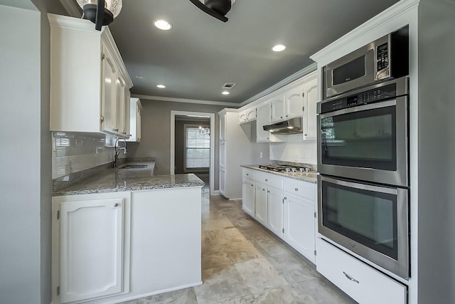 kitchen featuring white cabinets, sink, ornamental molding, light stone counters, and stainless steel appliances