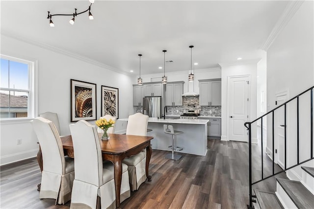 dining space with dark hardwood / wood-style floors, track lighting, sink, and ornamental molding