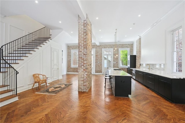 810 Bourbon St, New Orleans, LA 70116 - kitchen with dark cabinetry, a breakfast bar, a center island, ornate columns, and light countertops