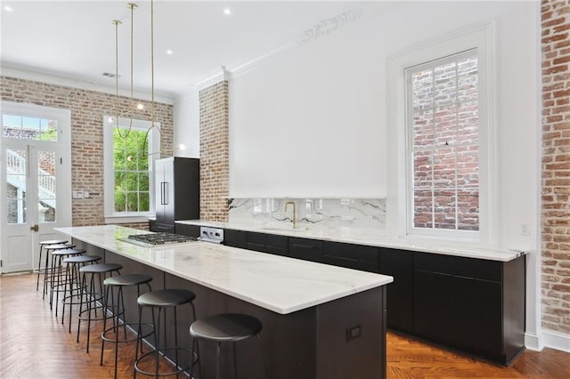 810 Bourbon St, New Orleans, LA 70116 - kitchen featuring stainless steel appliances, a sink, a kitchen bar, a spacious island, and dark cabinetry