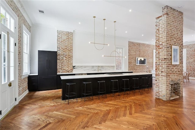 810 Bourbon St, New Orleans, LA 70116 - kitchen with brick wall, light countertops, dark cabinets, a kitchen bar, and a spacious island