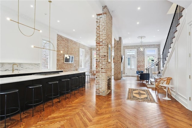 810 Bourbon St, New Orleans, LA 70116 - bar featuring brick wall, stainless steel gas stovetop, ornate columns, hanging light fixtures, and stairs