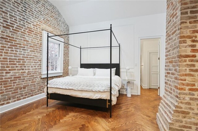 810 Bourbon St, New Orleans, LA 70116 - bedroom featuring lofted ceiling, brick wall, and baseboards