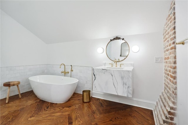 810 Bourbon St, New Orleans, LA 70116 - bathroom featuring a freestanding bath, vanity, tile walls, a wainscoted wall, and vaulted ceiling