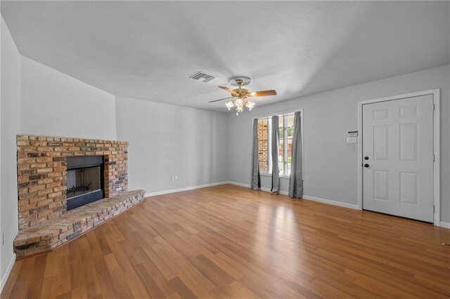 unfurnished living room featuring a brick fireplace, ceiling fan, and light hardwood / wood-style flooring