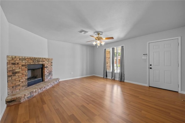 unfurnished living room with ceiling fan, light wood-type flooring, and a brick fireplace