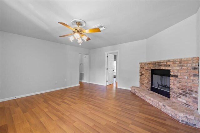 unfurnished living room with light wood-type flooring, a brick fireplace, and ceiling fan