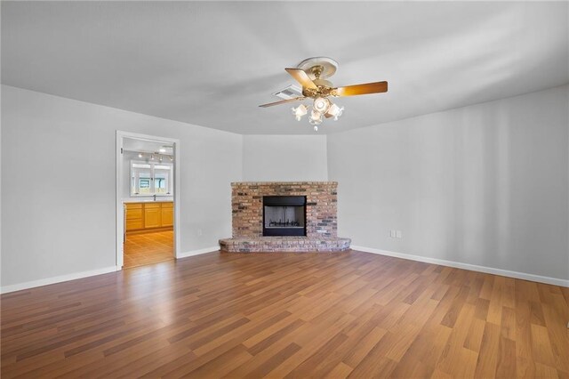 unfurnished living room with ceiling fan, wood-type flooring, and a fireplace