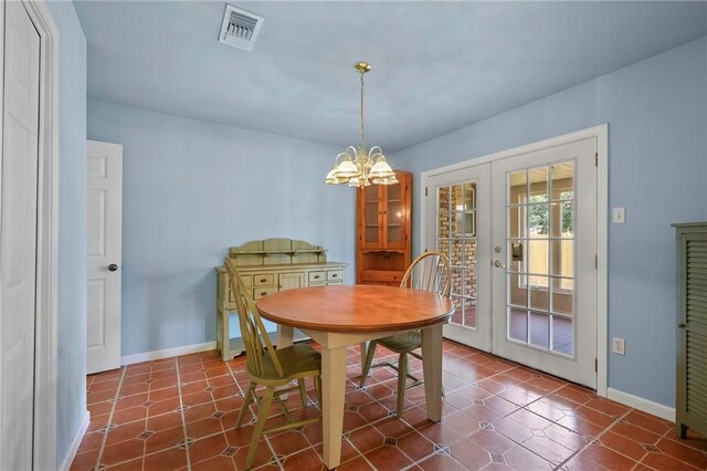 dining room featuring dark tile patterned floors, a notable chandelier, and french doors