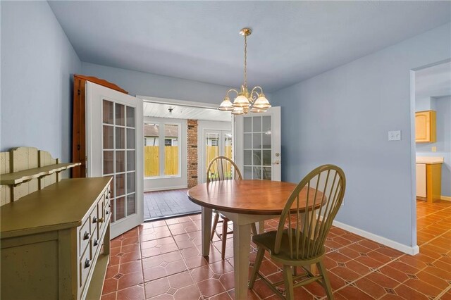 tiled dining space with a chandelier and french doors