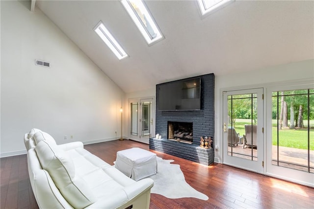 living room with a fireplace, dark hardwood / wood-style flooring, a skylight, and high vaulted ceiling