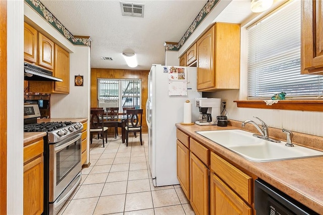 kitchen with white fridge, range with two ovens, sink, a textured ceiling, and light tile patterned floors