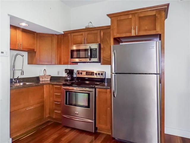 kitchen featuring sink, appliances with stainless steel finishes, dark stone counters, and dark hardwood / wood-style flooring