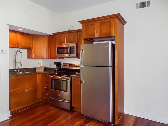 kitchen featuring dark stone countertops, sink, appliances with stainless steel finishes, and dark hardwood / wood-style floors