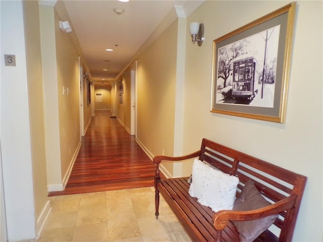 corridor with crown molding and light tile patterned floors