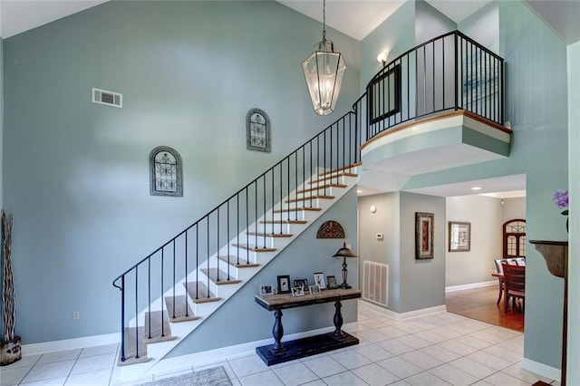 stairs with a notable chandelier, a high ceiling, and tile patterned flooring