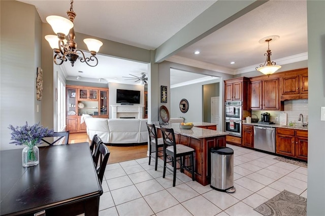 kitchen featuring a kitchen island, a breakfast bar, pendant lighting, appliances with stainless steel finishes, and ceiling fan with notable chandelier