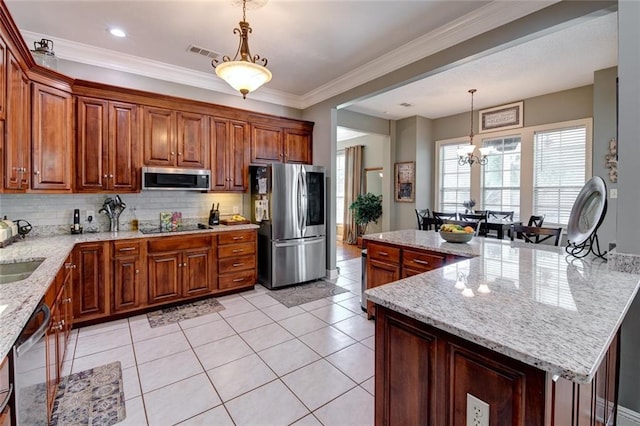 kitchen with light stone countertops, a kitchen island, stainless steel appliances, pendant lighting, and an inviting chandelier