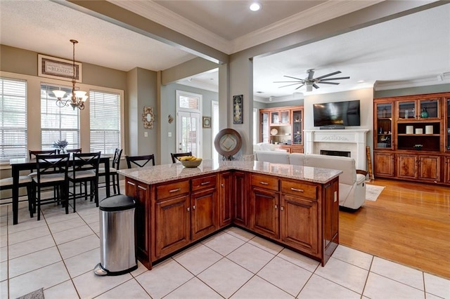 kitchen featuring light hardwood / wood-style flooring, decorative light fixtures, light stone counters, and crown molding