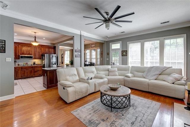 living room featuring ornamental molding, light hardwood / wood-style floors, and ceiling fan