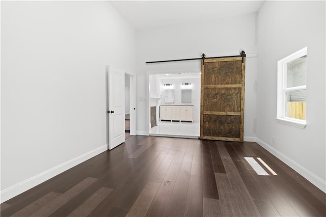 spare room featuring a barn door, dark hardwood / wood-style flooring, and a high ceiling