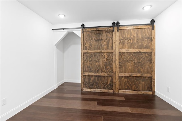 bonus room with dark hardwood / wood-style floors and a barn door