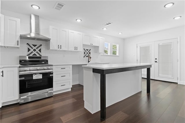 kitchen featuring white cabinets, a center island, stainless steel range, and wall chimney exhaust hood